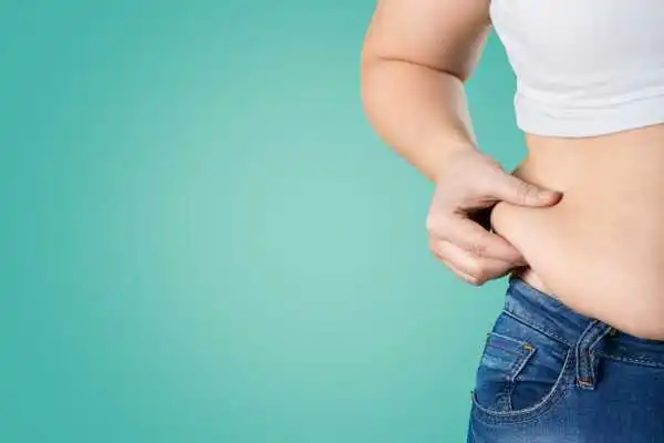 Image of woman pinching her love handles to show weight gain Almondsbury
